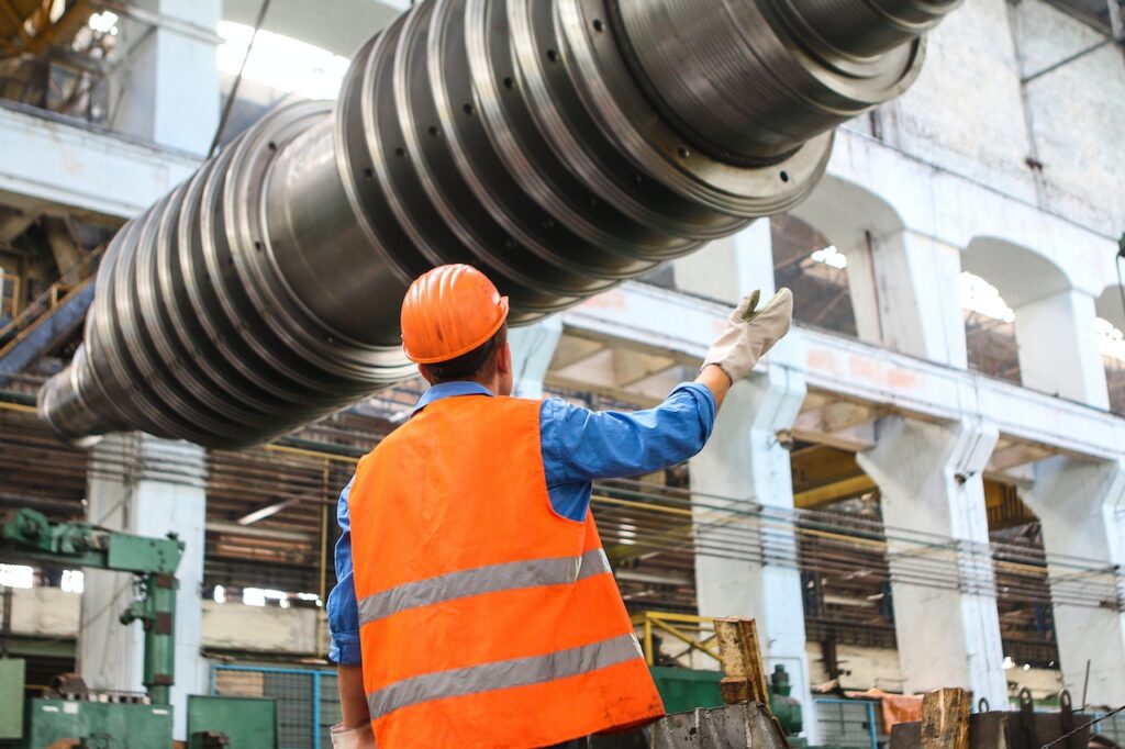 Gestão industrial - Homem na fábrica ajustando uma peça grande