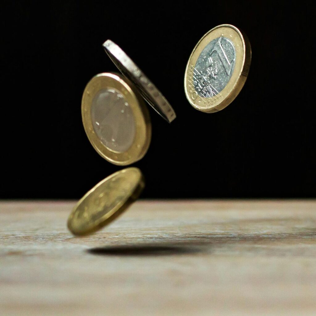 gestão de verbas - Modeas de 1 real caindo sobre uma mesa de madeira